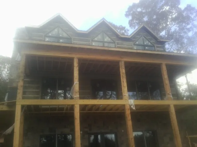 Dormers and porch framing on a large log home under construction — Roof Coating work by our crew in North Canton