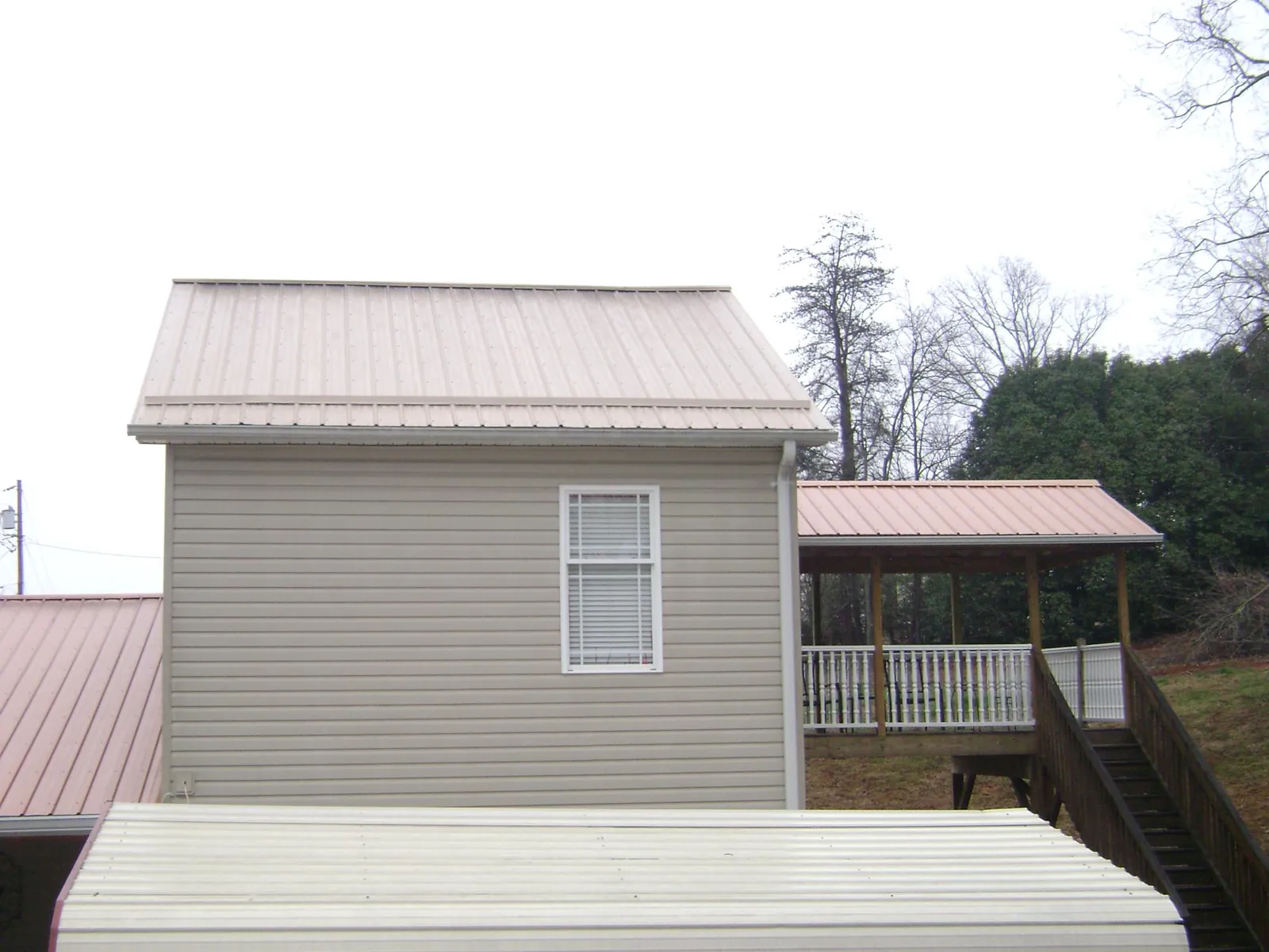 Tan metal roofs on a two story addition and attached porch, from a Roof Replacement job in North Canton