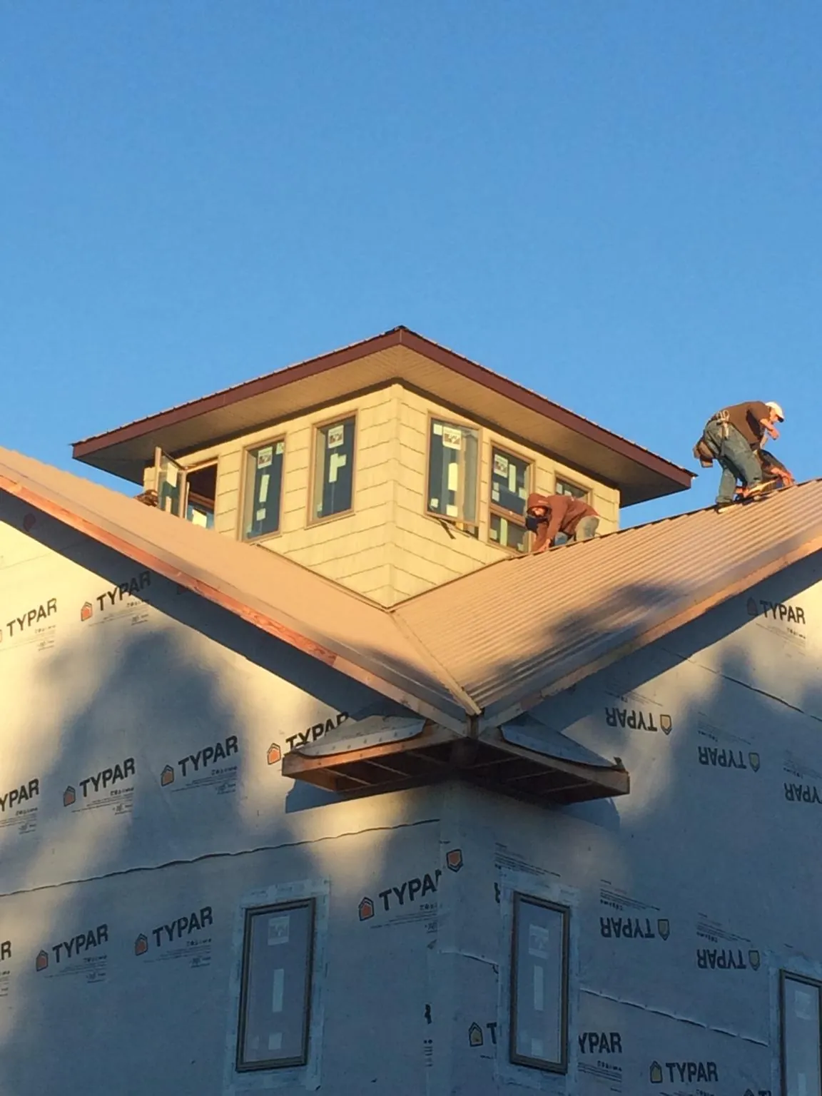 Roofers working around a rooftop cupola on a new metal roof at sunset — Roof Waterproofing in North Canton by Roofing Brothers